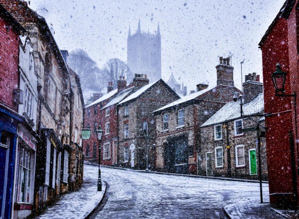 A snowy scene of Steep Hill in Lincoln, with the Cathedral in the background.