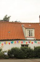Picture of Pow Cottage showing a long single story white cottage with a red/orange pan-tiled roof.