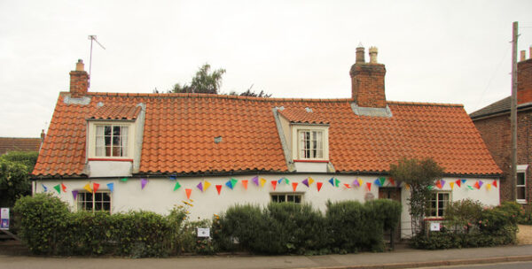 Picture of Pow Cottage showing a long single story white cottage with a red/orange pan-tiled roof.