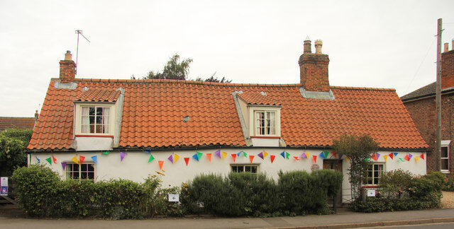 Picture of Pow Cottage showing a long single story white cottage with a red/orange pan-tiled roof.